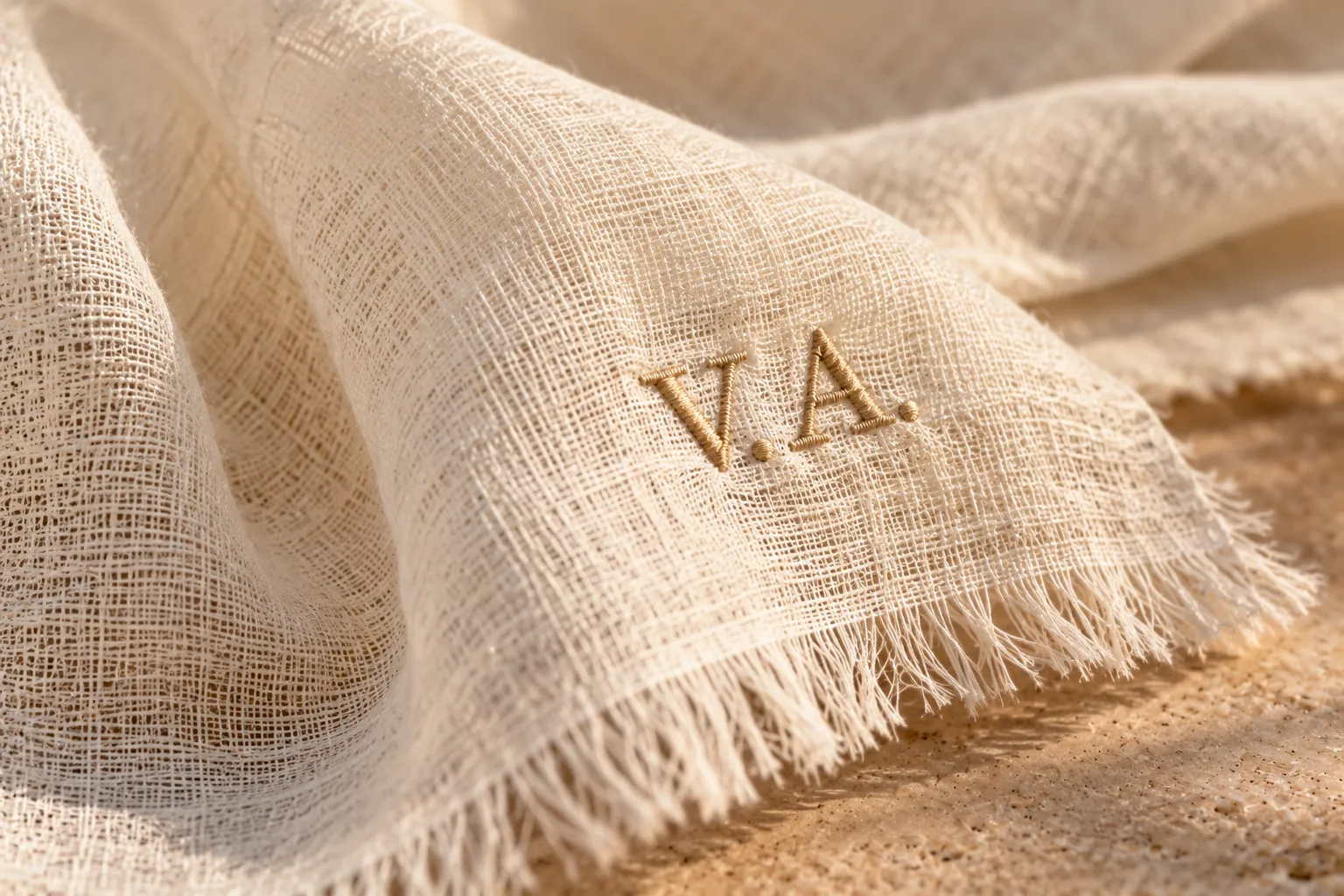 Hand-embroidered V.A. monogram on a natural-fibre shawl